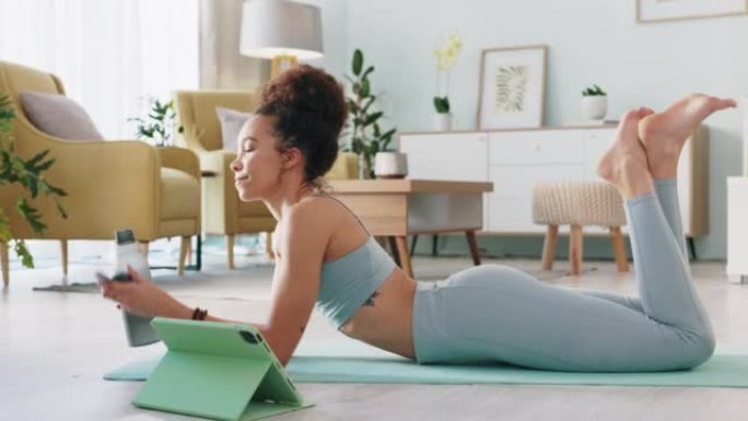 水，平板电脑和女人在她的房子的客厅地板上进行健身训练和有氧运动的在线视频。在互联网上锻炼和锻炼过程中