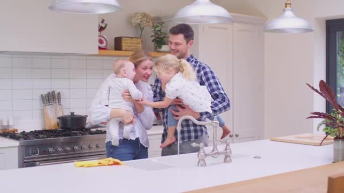 家庭在厨房里，父母在做家务后抱着孩子