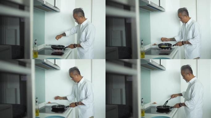 亚洲中国高级男子早上在厨房用炊具打破蛋壳煎蛋准备早餐