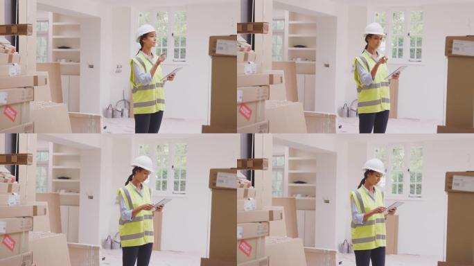 戴着带数字平板电脑的安全帽的女建筑商检查物业内新厨房单元的交付-慢动作拍摄