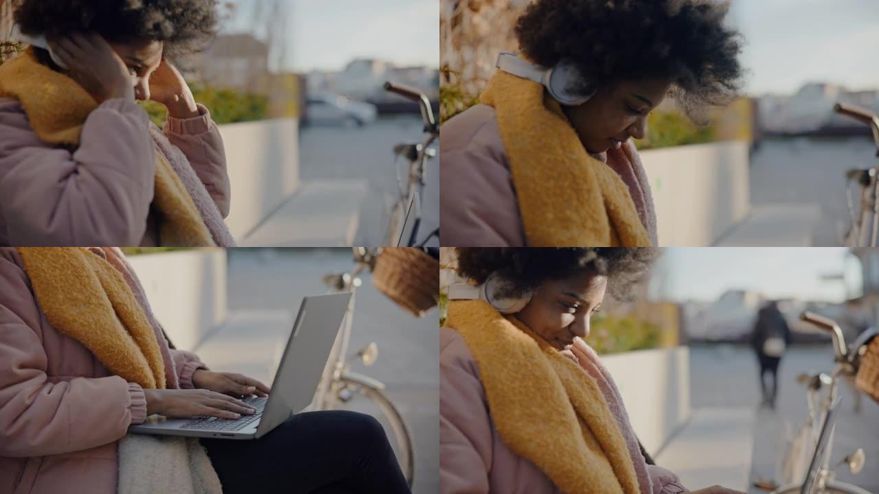 年轻的黑人女士在城市开始使用笔记本电脑之前，将无线耳机戴在耳朵上