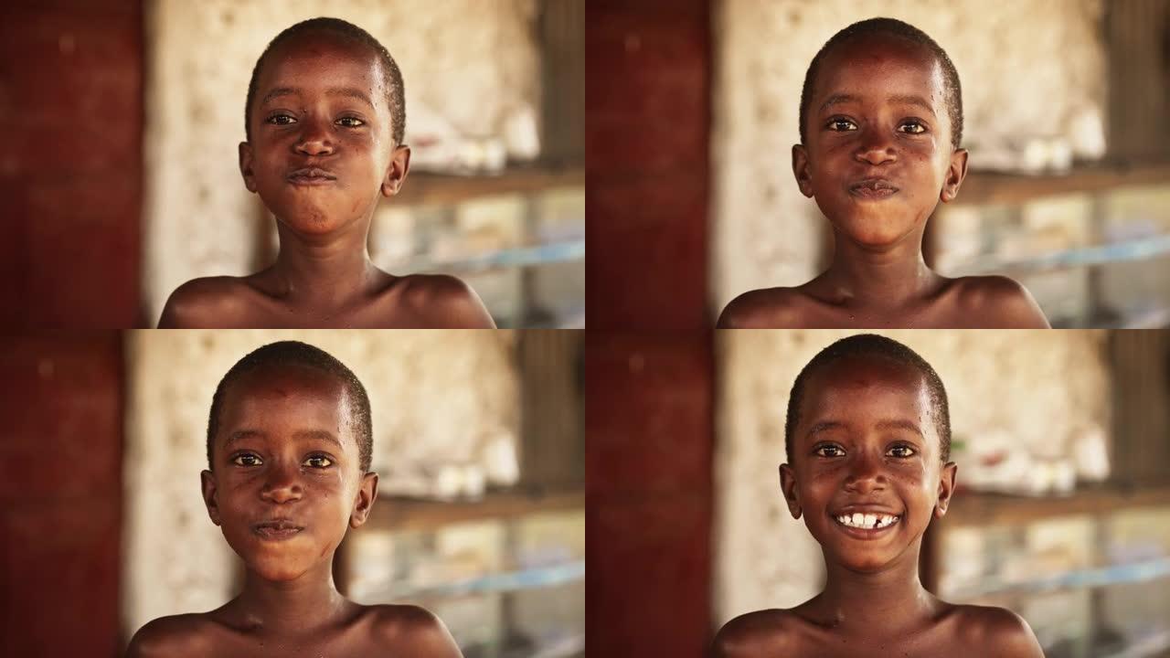 特写一个真实的非洲小男孩看着镜头，笑着然后微笑。黑人儿童代表希望、平等、团结。纪录片的概念