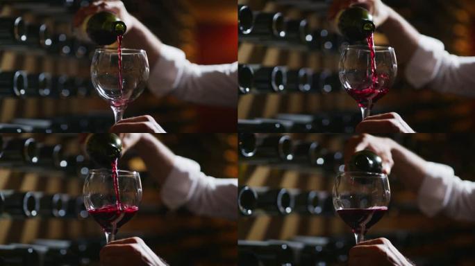 近距离拍摄酿酒师或侍酒师正在检查酒窖中倒入透明玻璃杯中的红酒的质量。