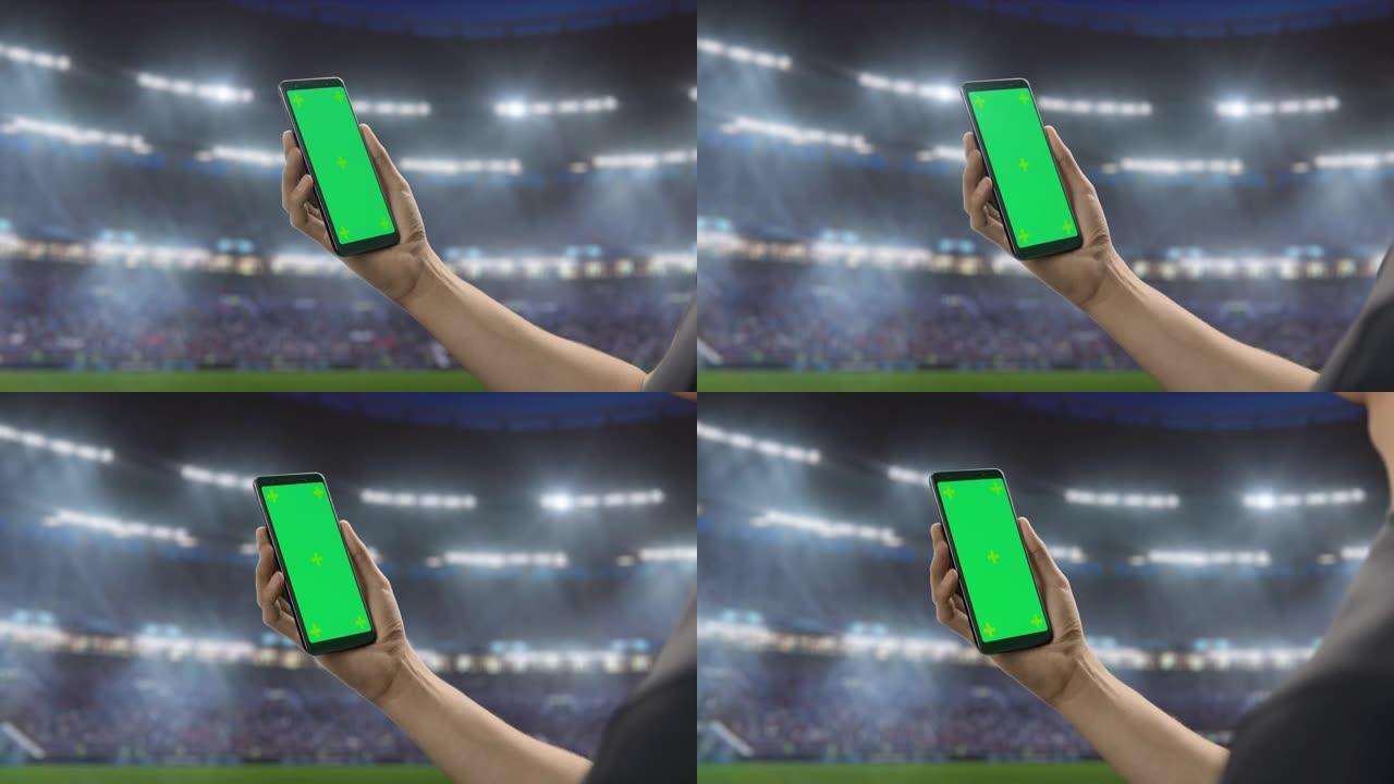 体育场馆锦标赛: 手持绿屏色度键智能手机的人的手。体育赛事，球迷为最喜欢的球队赢得冠军而欢呼。孤立的
