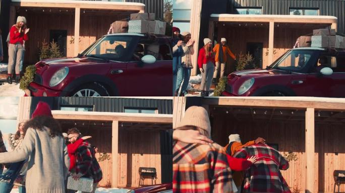 节日气氛。快乐的年轻夫妇开着红色的汽车，上面有礼物，在雪屋慢动作中会见兴奋的朋友。