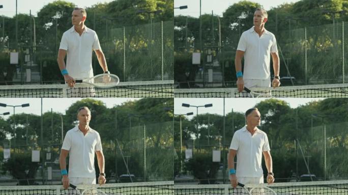 成熟的男人在网球场上拿着网球拍四处张望