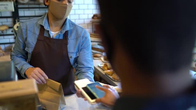 在面包店中使用智能手机通过NFC付款的客户