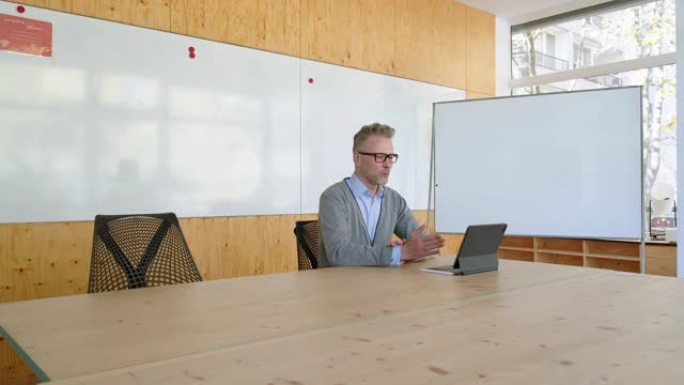 成熟的初创公司首席执行官在办公室通过数字平板电脑进行视频会议
