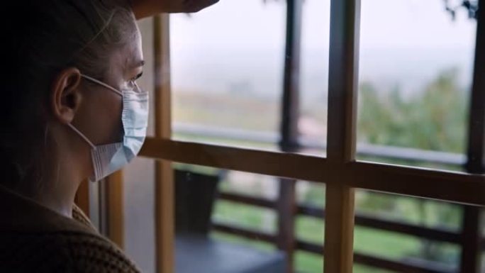 SLO MO女人戴着面具，透过窗户看，回忆新型冠状病毒肺炎禁闭期间的自由