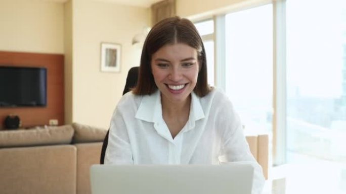 快乐的漂亮女人在笔记本电脑上阅读好消息感到喜出望外