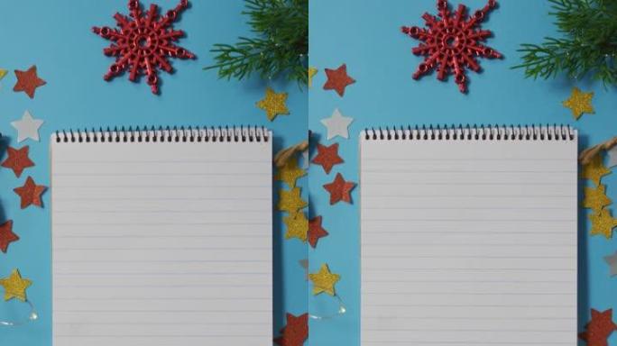 蓝色背景上的圣诞节装饰品包围着笔记本的垂直头顶照片