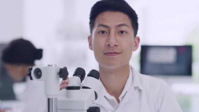 在实验室里使用显微镜的男科学家。一个快乐的年轻生物学家或生物技术研究员的肖像工作与最新的实验室仪器在