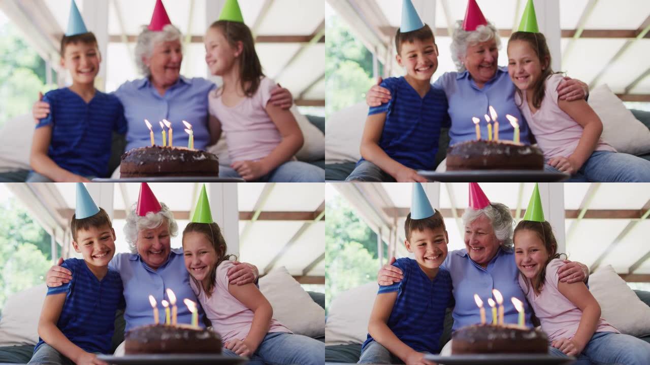 戴着党帽的白人高级妇女在家里的桌子上抱着孙子孙女，用生日蛋糕拥抱她