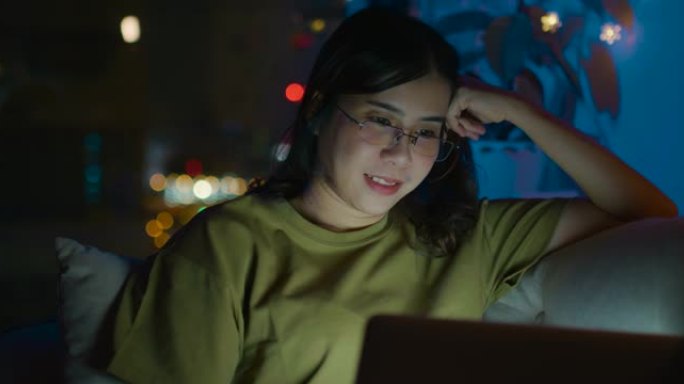 年轻女子坐在沙发上，深夜使用笔记本电脑。观看内容