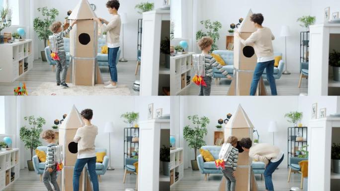 幸福的家庭母亲和儿子在公寓里一起制作纸板火箭