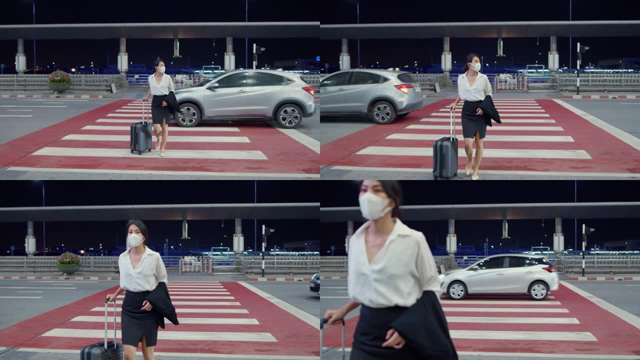 亚洲商务女孩到达目的地戴着口罩，带着行李在国内机场候车厅外行走。