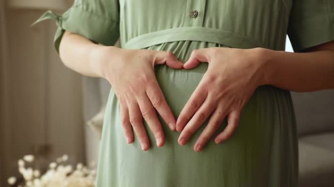 孕妇将手臂放在大肚子上，形成心形