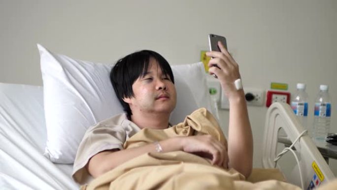 亚洲男子病人在医院床上通话手机