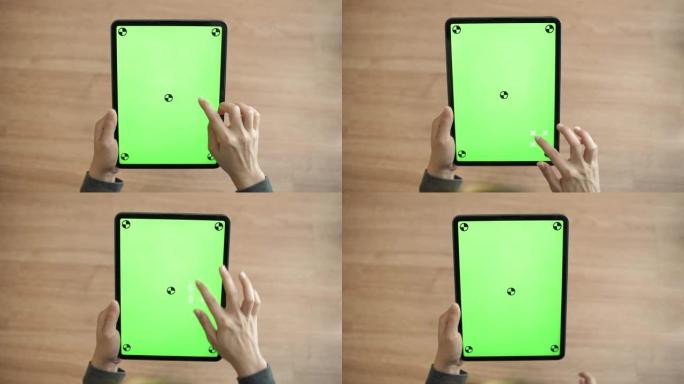 在家里的办公桌上使用带有绿色屏幕的数字平板电脑的特写手