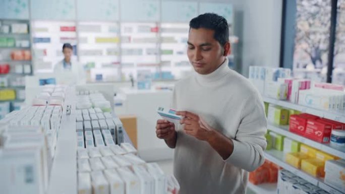 药房药店: 肖像英俊的印度男子选择买药浏览货架，成功找到他需要的东西，开心地微笑。现代制药商店保健产