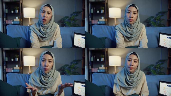 年轻的亚洲穆斯林妇女戴着头巾，心烦意乱的妇女拿着笔记本电脑看相机在线电话会议讨论工作感觉心情不好，员