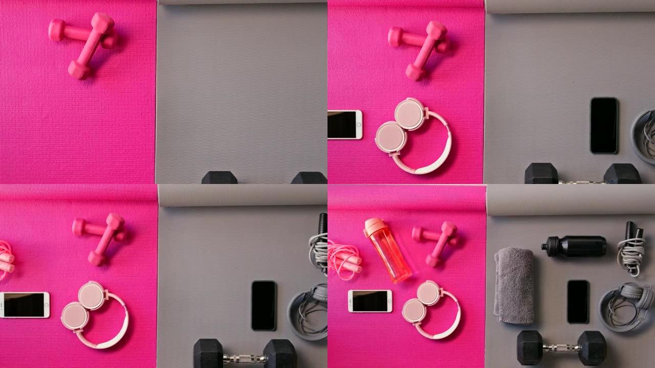 粉色和灰色瑜伽垫，上面装满健身器材。手机、耳机、健身器材、鞋子放在空旷的工作室里。通过有氧运动和举重