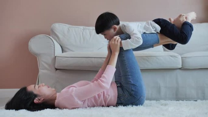 快乐美丽的亚洲家庭健康的年轻妈妈和可爱的小孩儿子在家在地板上锻炼