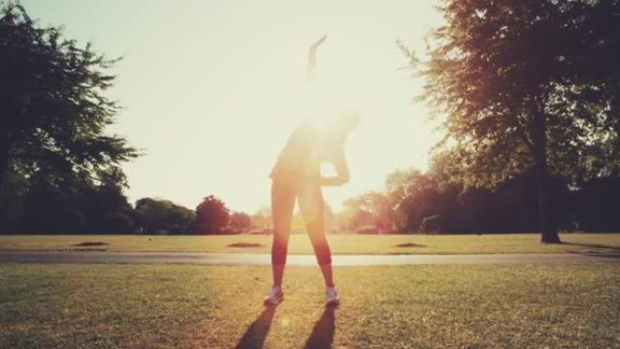 4k视频片段，一个无法辨认的女人在公园里伸展，然后在外面晨练。