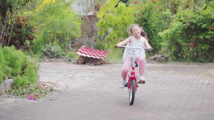 SLO MO可爱快乐亚洲小女孩骑红色自行车