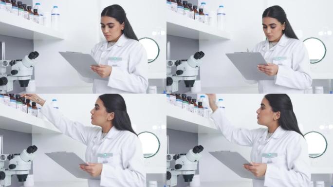 医学研究人员在现代实验室的架子上检查药品样品产品。年轻的专注科学家或药剂师在实验室写笔记时查看库存并