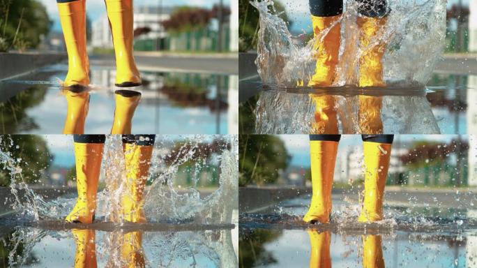 特写无法辨认的穿黄色胶靴的女孩跳进玻璃水坑