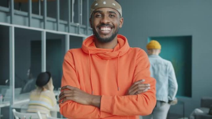 快乐的美国黑人男子微笑站在同事空间的慢动作肖像