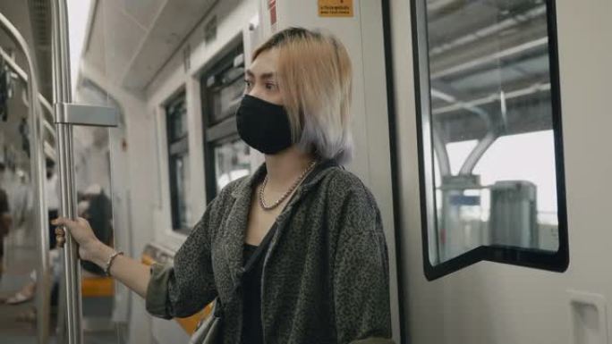 在BTS Skytrain上戴着口罩的亚洲女性。