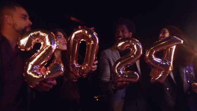 一群朋友拿着2024气球和烟火庆祝新年