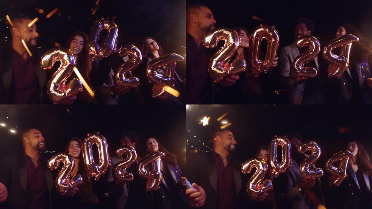 一群朋友拿着2024气球和烟火庆祝新年