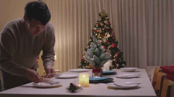 亚洲单身男子今晚准备圣诞夜餐桌布置派对。
