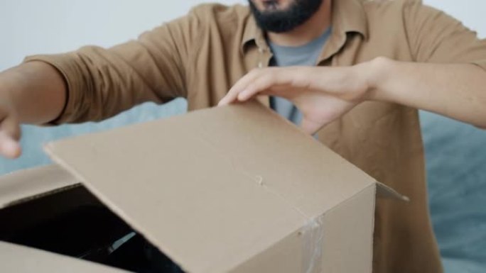 搬迁过程中男性手打开纸箱拆包物品的特写