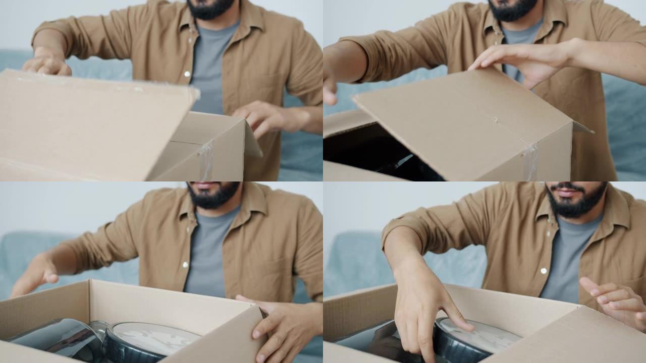 搬迁过程中男性手打开纸箱拆包物品的特写