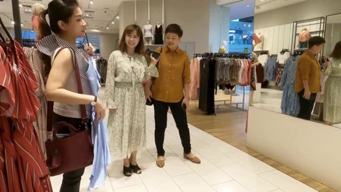 亚洲华人女性在服装店看镜选择衣服