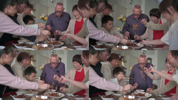 亚洲华人mutli世代家庭在团圆饭中与传统美食Lou sang (生鱼菜) 庆祝除夕
