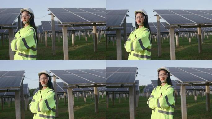 穿着防护服和头盔的女工站在太阳能电池太阳能电池板前，双臂交叉。用于与使用太阳能的可再生能源相关的应用