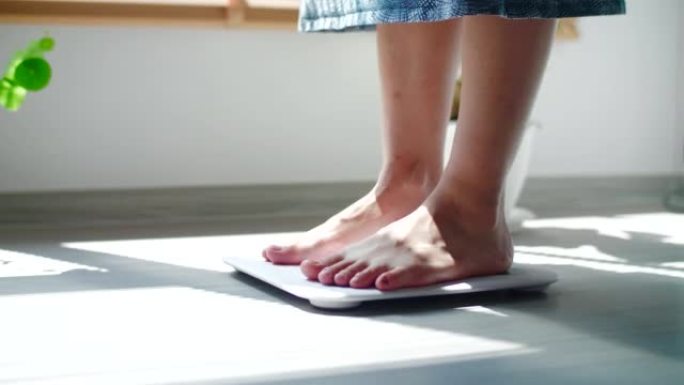 女人在家里客厅的体重秤上检查体重的特写