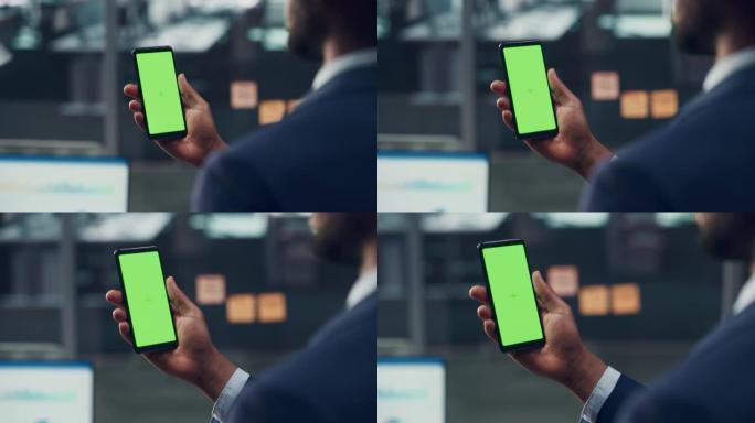 办公室里有绿屏色度键智能手机的黑人商人。非裔美国人商人使用互联网，社交媒体，使用手机设备进行在线购物