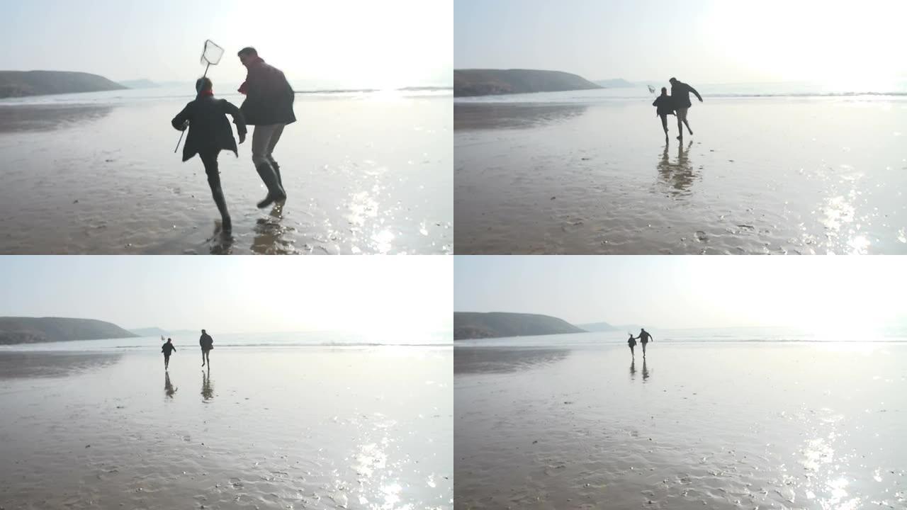 父亲和儿子在带有渔网的冬季海滩上奔跑