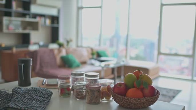 从厨房柜台观看水果篮和小吃前景以及客厅沙发和窗户背景的平移拍摄