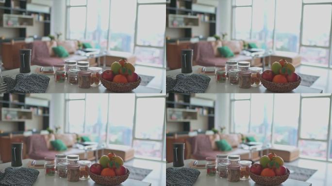 从厨房柜台观看水果篮和小吃前景以及客厅沙发和窗户背景的平移拍摄