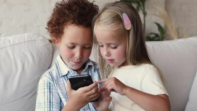 学龄前儿童坐在家里的沙发上使用智能手机