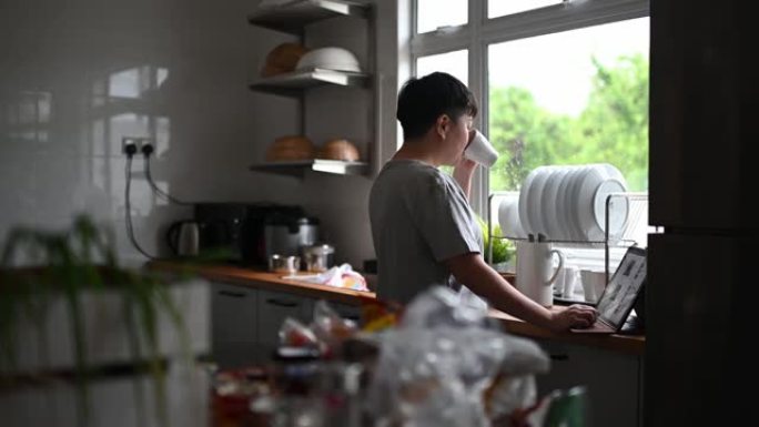 亚洲中国成熟女性在厨房使用数字平板电脑上网休息