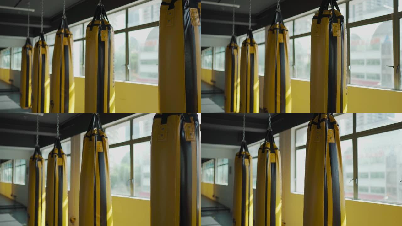 健身房健身俱乐部，一排黄色出气筒沙袋旁边窗口白天时间