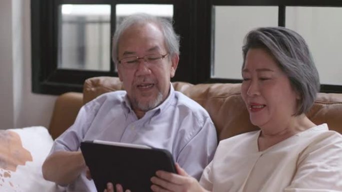 祖父和祖母坐在工作中在家中使用平板电脑，这是老年人使用现代技术的学习。在没有病毒的检疫期间。